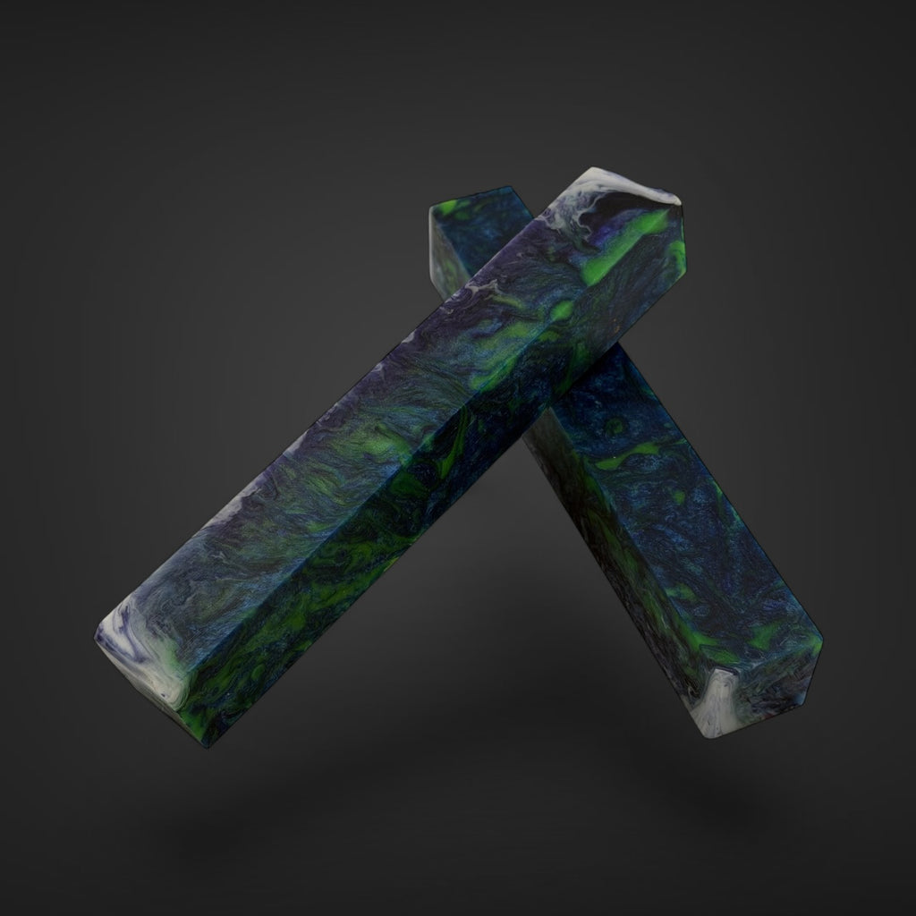 Two polished crystal points with a marbled pattern of green, blue, and white, crossed over each other against a dark gray gradient background. JHC resin chaos pen & bead blanks 