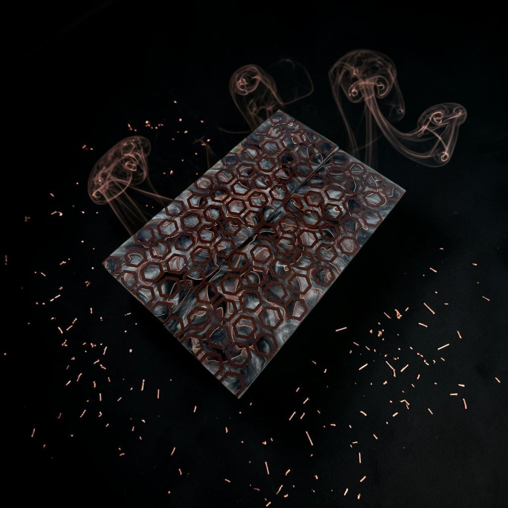 A rectangular glass plate featuring a copper-colored honeycomb pattern, displayed on a dark background with stylized smoke and copper-colored sparkles.