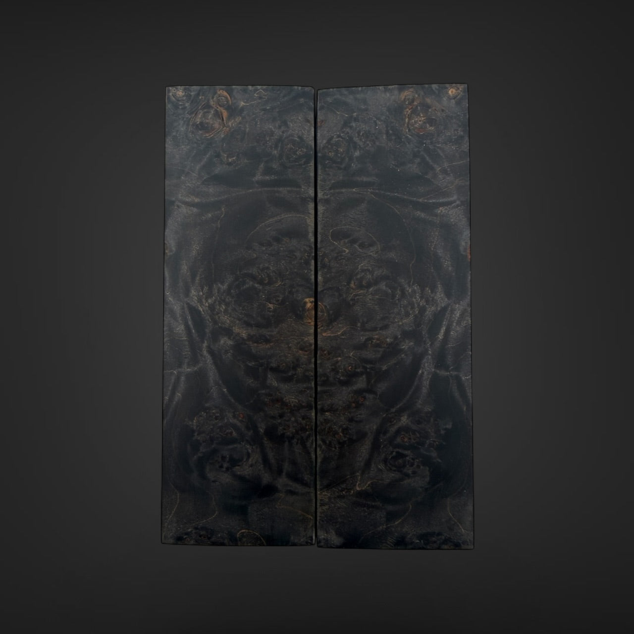 Male Burl knife scales. A dark, double-panel folding screen or decorative wall art piece featuring an intricate, low-contrast black and charcoal pattern with subtle warm metallic-looking highlights, centered against a dark gray gradient background.